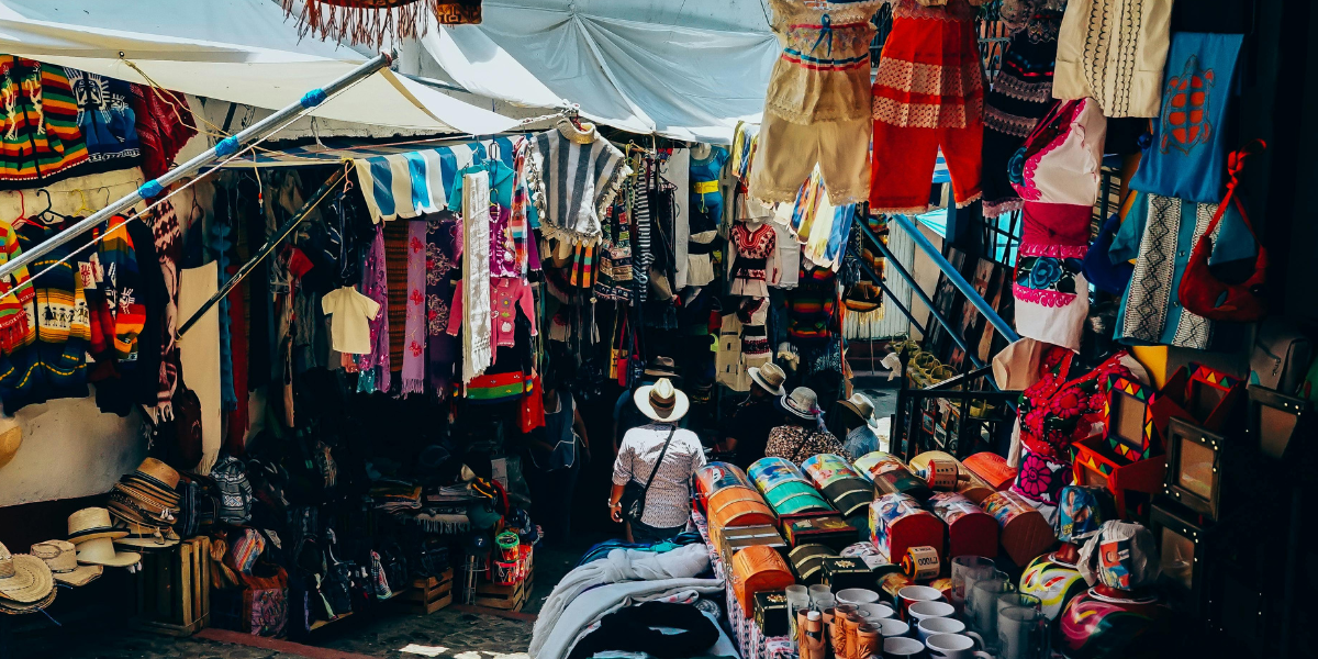 Goods Getaways travelers shopping at a vibrant local artisan market.