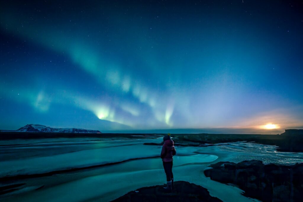 A traveller enjoying Northern Lights during an off-peak getaway under a vibrant night sky.